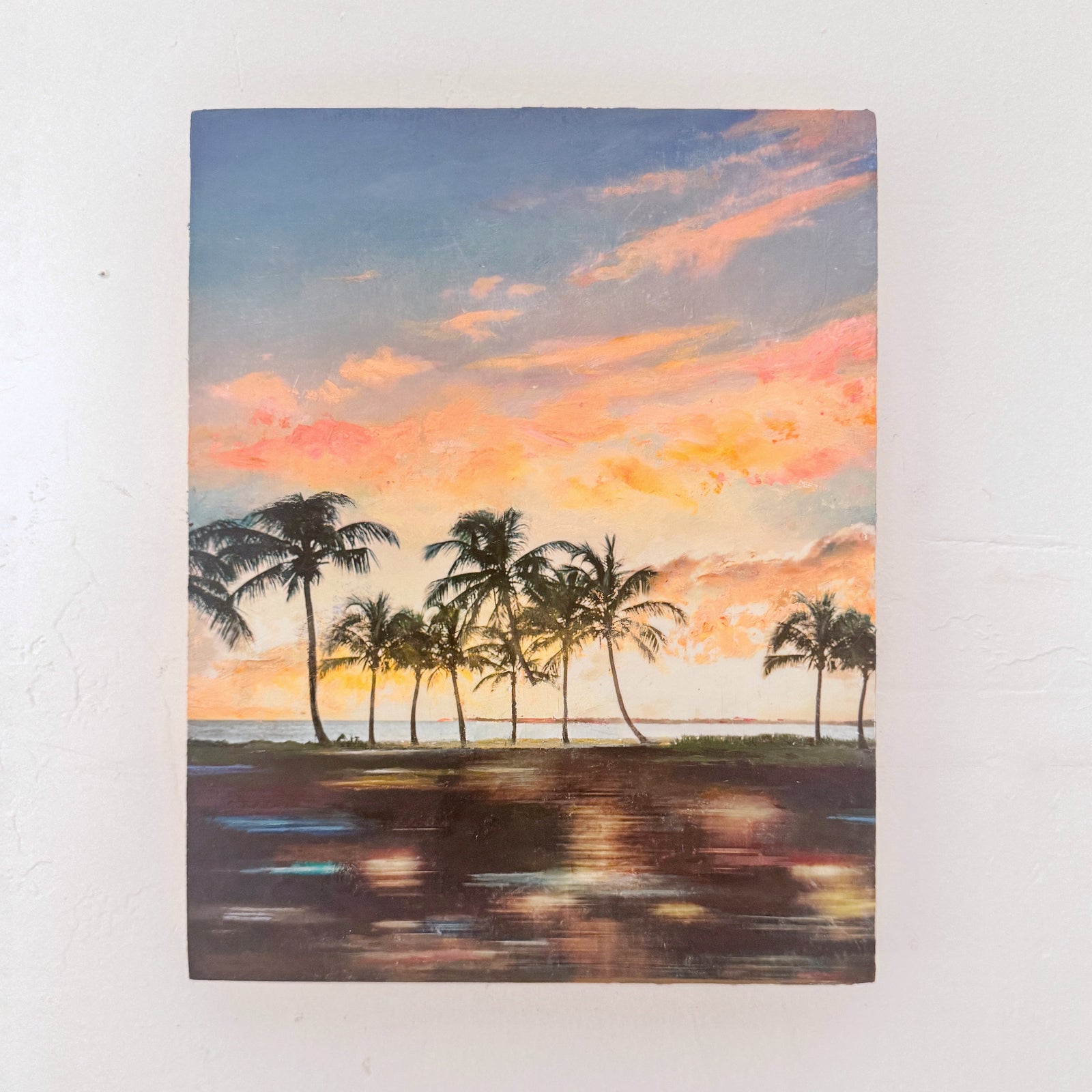 original painting of a coastal sunset with palm trees on a white wall. neon colors. 