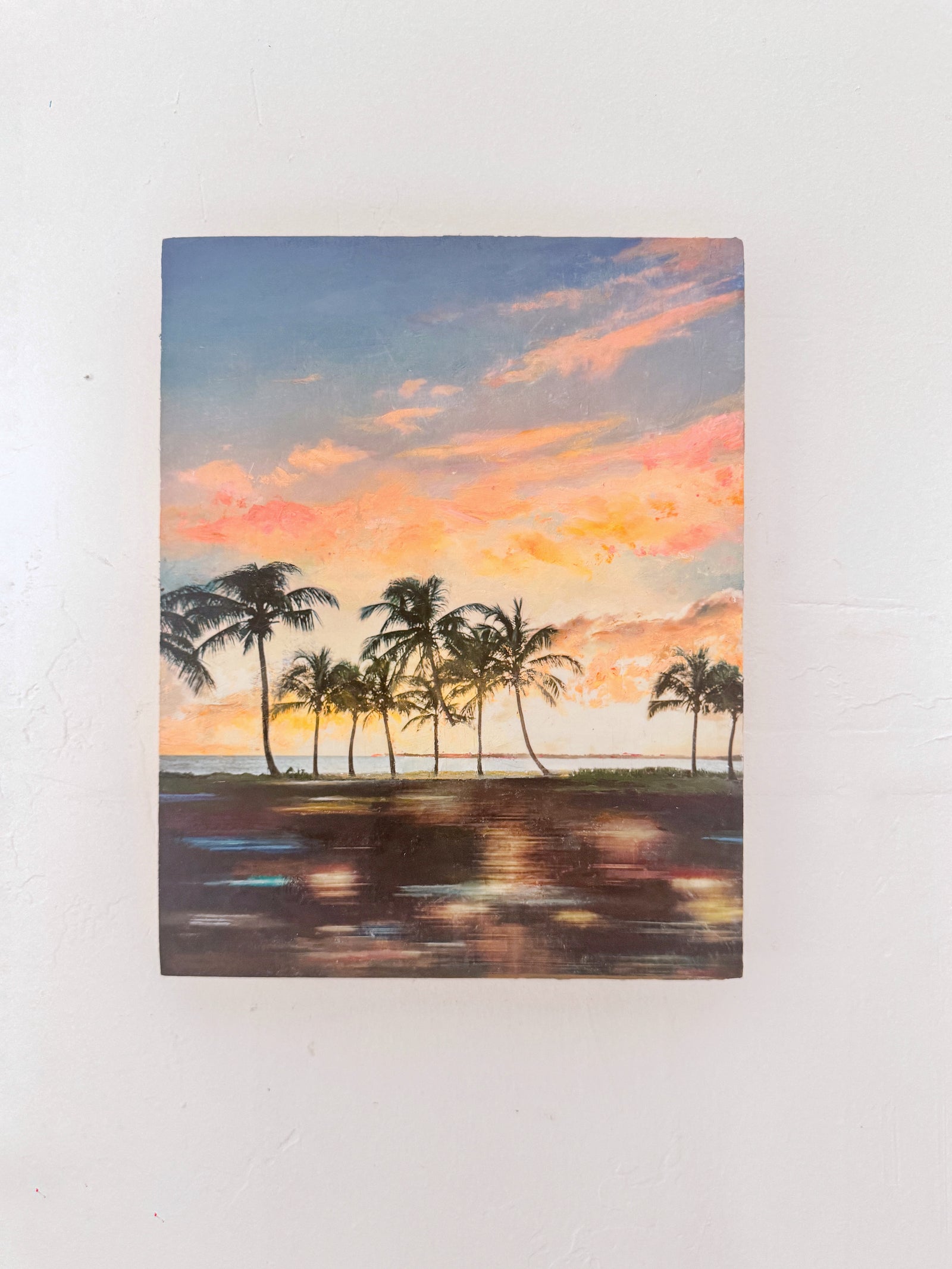 original painting of a coastal sunset with palm trees on a white wall. neon colors. 